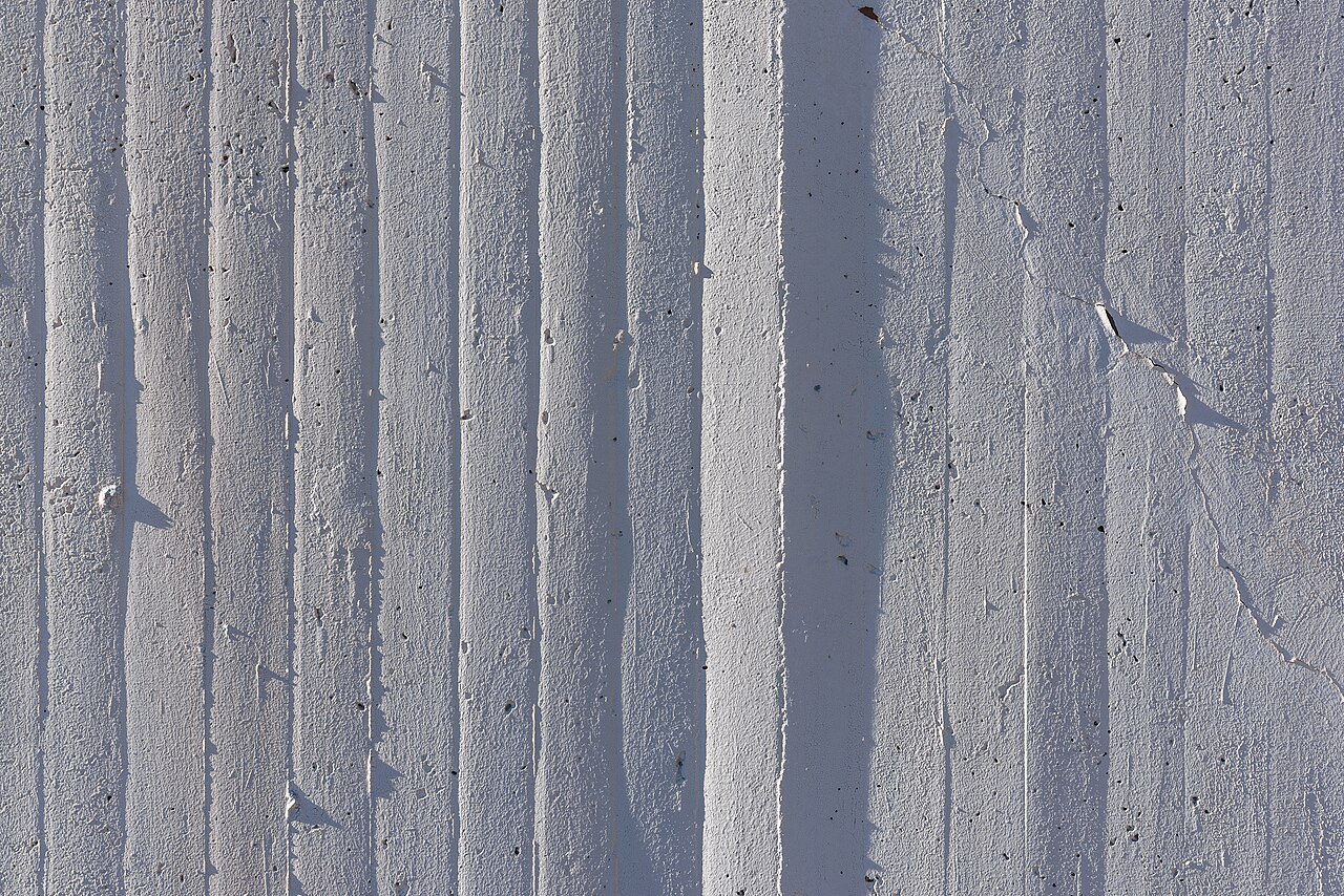 A concrete wall with the grain of the wooden form boards printed into its surface